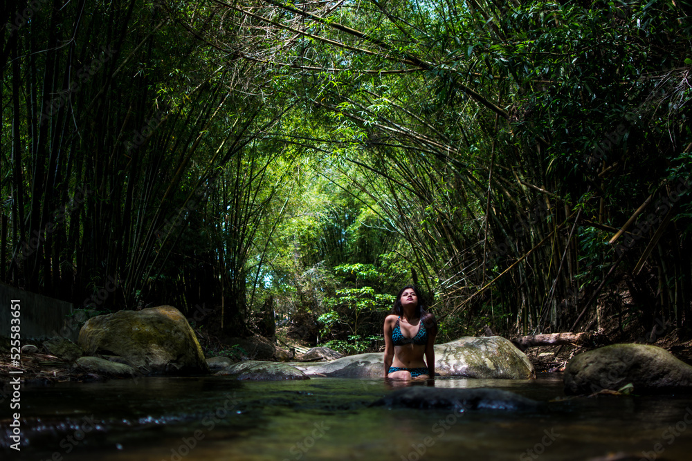 Girl on vacation in a spa. Girl bathing in a river. Woman with hat. River with stones and bamboo Girl on vacation in a spa. Girl bathing in a river. Woman with hat. River with stones and bamboo