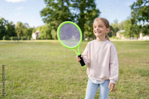 Preschooler girl playing badminton in summer park. © Julija