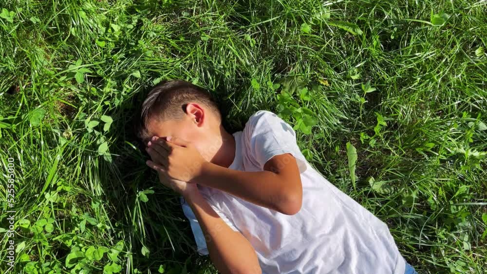 A young boy lies in the grass, smiling, hiding his face. A young boy lies in the grass, smiling, hiding his face.
