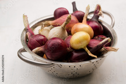 Purple, white and golden onions in a sieve