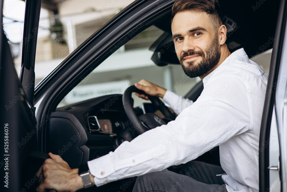 Man sitting in car in a car showroom Man sitting in car in a car showroom