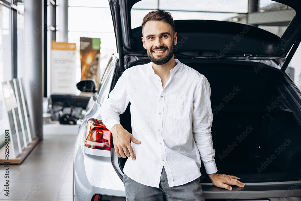 Young man in car showroom choosing a car