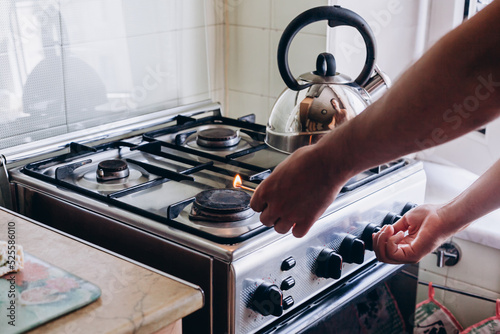 A man's hand with a match lights a gas burner or a gas stove in the kitchen