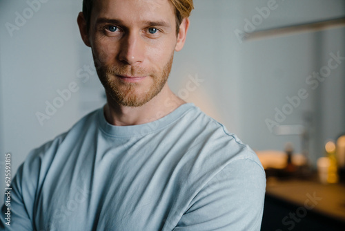 Young bearded white man wearing t-shirt smiling on camera at home