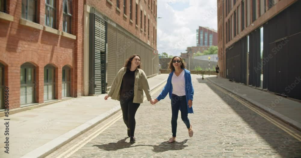 WS MS SLO MO Female couple walking in city and holding hands WS MS SLO MO Female couple walking in city and holding hands