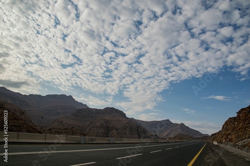 Empty asphalt road to Jebel Jais passing through a mountainous landscape on a sunny day in UAE photo