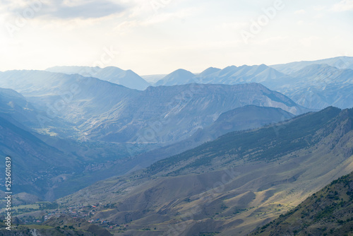 Amazing landscape of mountain range with sunset sky and clouds and rural village in mountain valley in Dagestan. Scenery of mountain layer at dusk. © sommersby