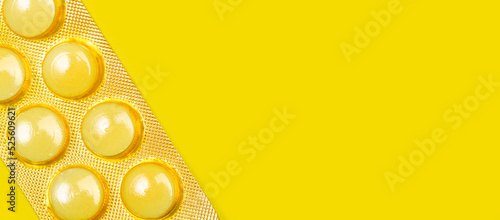 Blister de pastillas mediamentos amarillas sobre fondo amarillo brillante liso y aisado. Vista superior y de cerca. Copy space. Concepto: Banner de salud photo