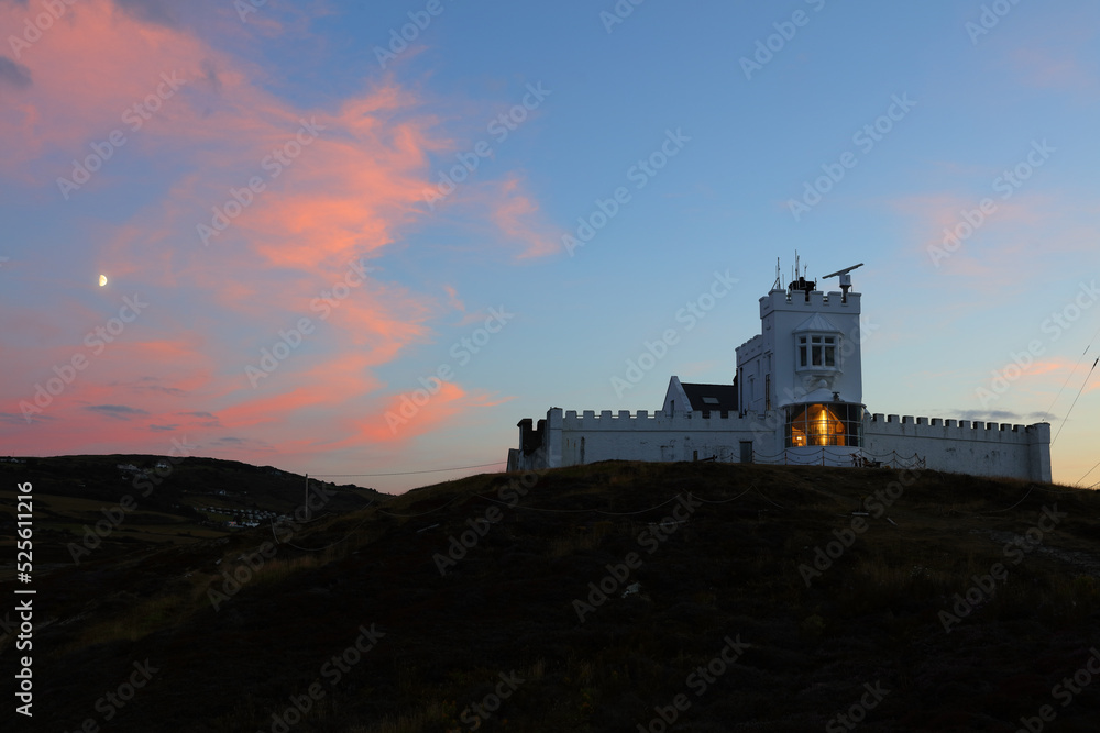 Point Lynas Lighthouse at Sunset with the Moon in the Sky. Anglesey, North Wales, UK.