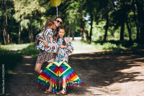 Mother with daughters in park holding balloons and kite