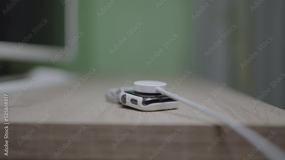 Slow motion of the charging cable is plugged into the smart watch on the wooden table. Slow motion of the charging cable is plugged into the smart watch on the wooden table.