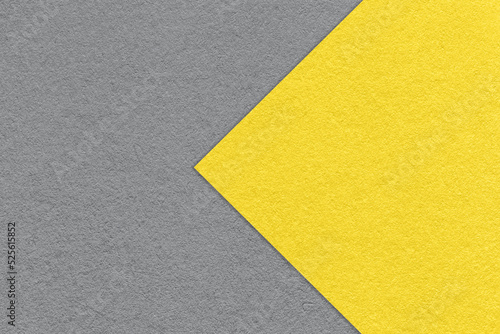 Texture of paper gray background, half two colors with yellow arrow, macro. Structure of dense craft cardboard