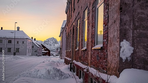 Snowy road by a building with brick wall on the sunset photo