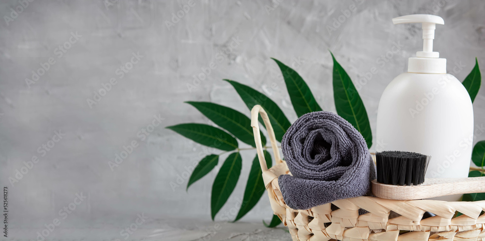 Gray towel, body massage brush, black bristle brush, foot penza, green ailanthus branch on gray background, bath accessories concept, bath products - obrazy, fototapety, plakaty 