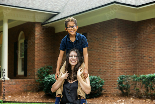 A big sister holding her little brother on her shoulders for a fun portrait