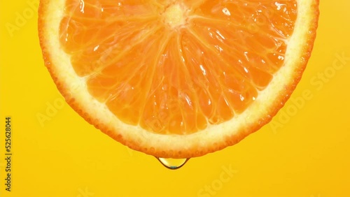 Water drop falling from orange hue orange on yellow background. Orange slice and water splashing, drops of juice falling from juicy fruit. Making cocktail of fruits, drinking cold lemonade