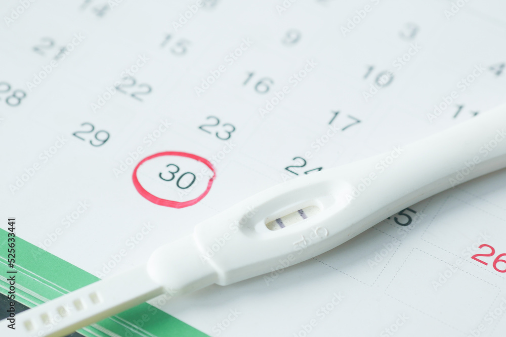 Pregnancy test kit on a calendar close up Pregnancy test kit on a calendar close up