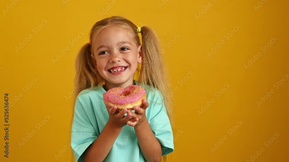 Funny girl laughs and holds a pink donut on a yellow background Funny girl laughs and holds a pink donut on a yellow background