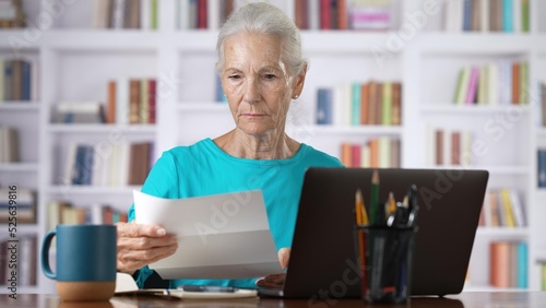Stressed senior woman holding letter troubled with domestic bills, bad news.