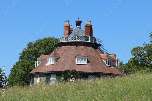 The roof of an unusual historic sixteen sided house on a beautiful sunny summers day in Devon, England seen from across the meadow garden.