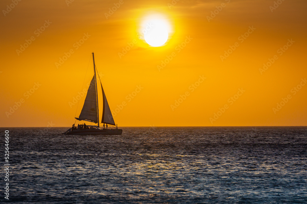 Idyllic beach with sailboat in Aruba at golden sunset, Dutch Antilles