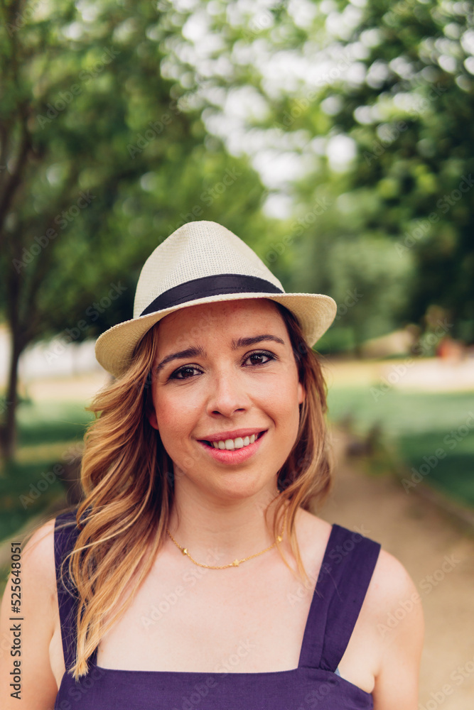 Portrait of a beautiful Caucasian woman outdoors with a hat and a perfect smile.