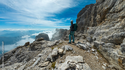Fotografie woman climbing the via ferrata via delle bocchette mountain sign in the brenta
