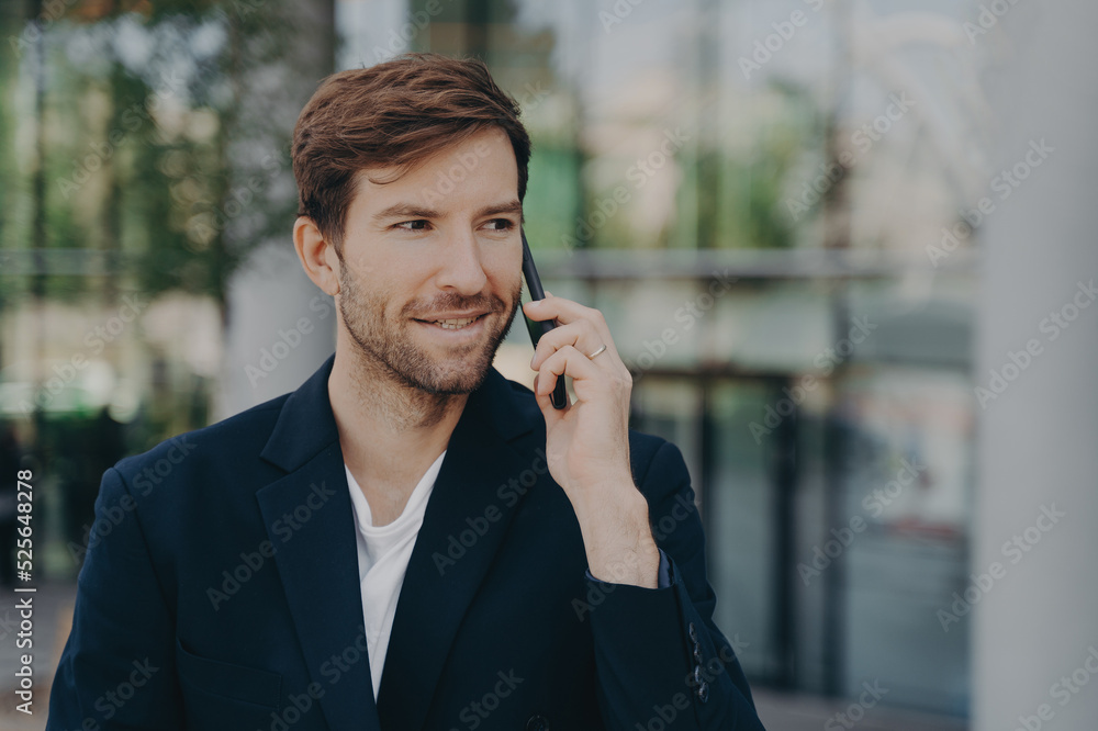 Handsome unshaven male executive worker left business building talks via smartphone Handsome unshaven male executive worker left business building talks via smartphone