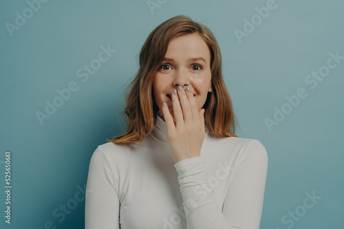 Astonished and shocked young woman in casual clothes covering her mouth with hand