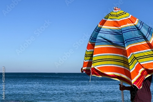 A man holding an open parasol on the beach photo