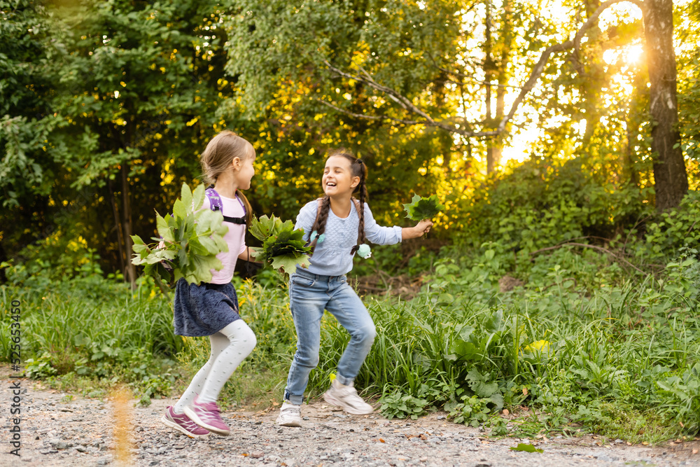 Fototapeta premium happy joyful school kids with backpacksin forest on autumn day, excited children girls having fun during camping activity in nature