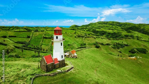 Aerial view of an old lighthouse under the blue sky in the green hills of Batanes photo