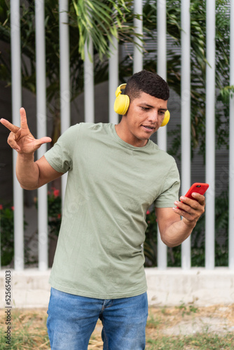 Portrait of a young man with headphones walking outdoors in the city, listening to music.