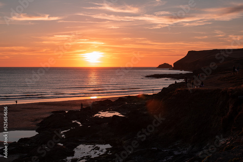 sunset on the beach sea cliffs polzeath cornwall endland low tide people walking flare 
