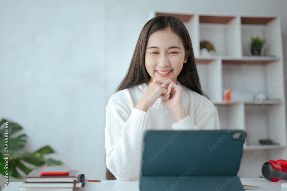 Young beautiful is studying online via tablet and writing on note book at home. Young beautiful is studying online via tablet and writing on note book at home.