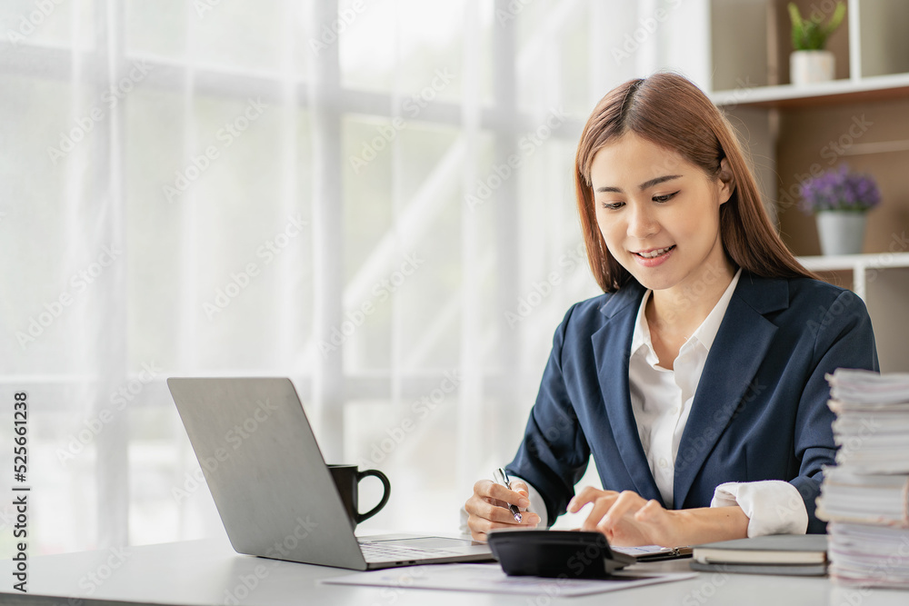 Charming Asian businesswoman or finance worker using a laptop computer and working on financial accounting reports in the office. Charming Asian businesswoman or finance worker using a laptop computer and working on financial accounting reports in the office.