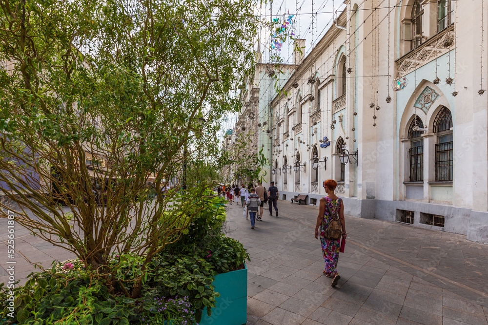 Pedestrian street decorated with blooming flowers bushes trees with people walking, Moscow, Russia