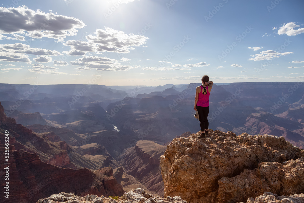 Adventurous Traveler standing on Desert Rocky Mountain American Landscape. Cloudy Sunny Sky. Grand Canyon National Park, Arizona, United States. Adventure Travel