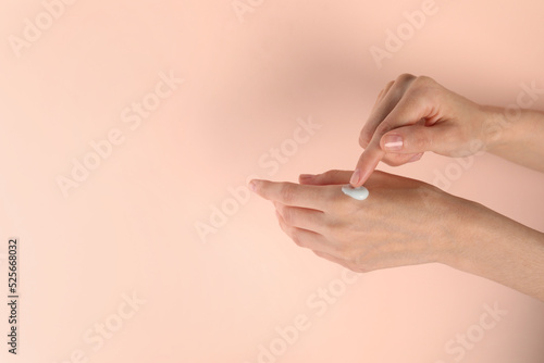 Woman applying hand cream on pink background  closeup. Space for text