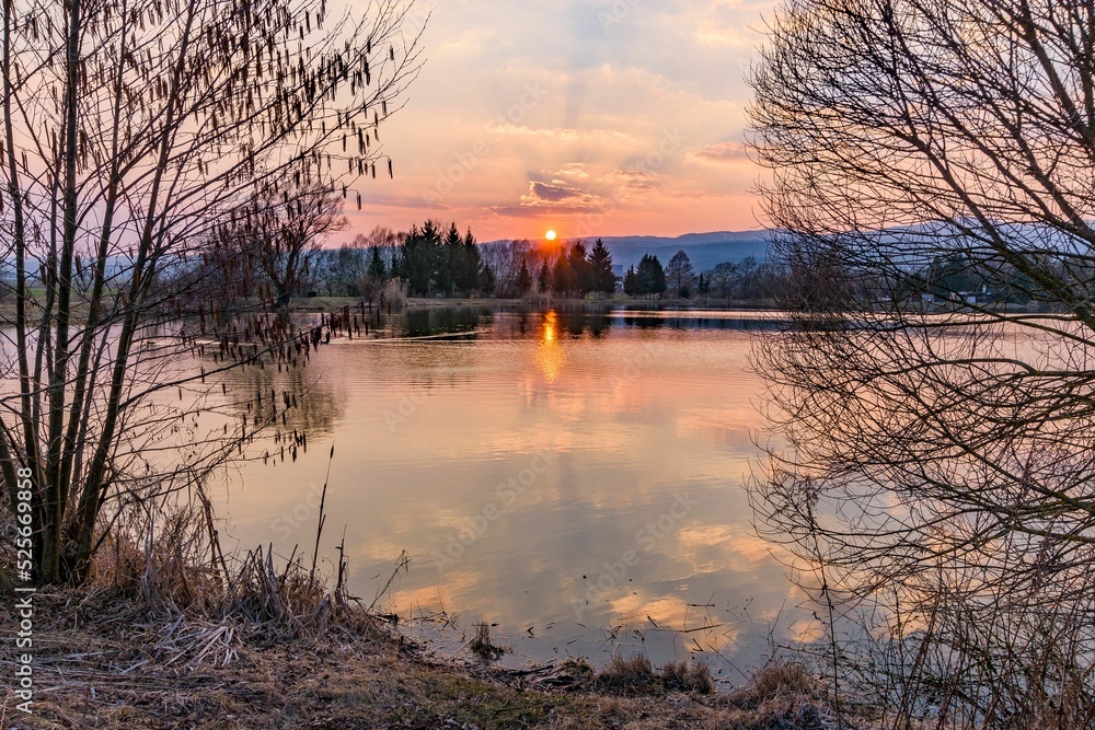 Obraz na płótnie Fishing pond Badinsky Rybnik during sunset from between dead trees in the central Slovakia w salonie