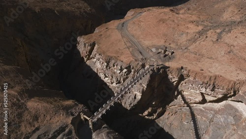 AERIAL 4K, drone flights forward in top of a rustic bridge in the possibly most dangerous road in the world, big drop under the bridge, then it continues following the road, way to Shimshal, Pakistan
