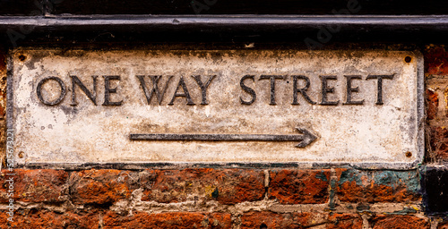 Old Weathered One Way Street Sign on a Wall with Arrow indicating Left to Right