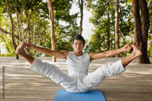 A yoga instructor practices yoga on the outdoor treetop platform overlooking Phang Nga Bay. Thailand. photo