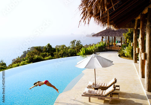 A woman dives into a private luxury infinity pool  overlooking Phang Nga Bay, Yao Noi, Thailand.