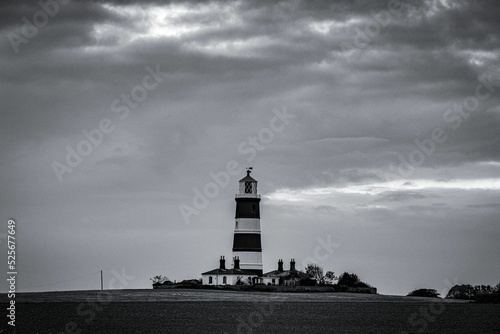 Grayscale shot of a lighthouse on the cloudy sky background