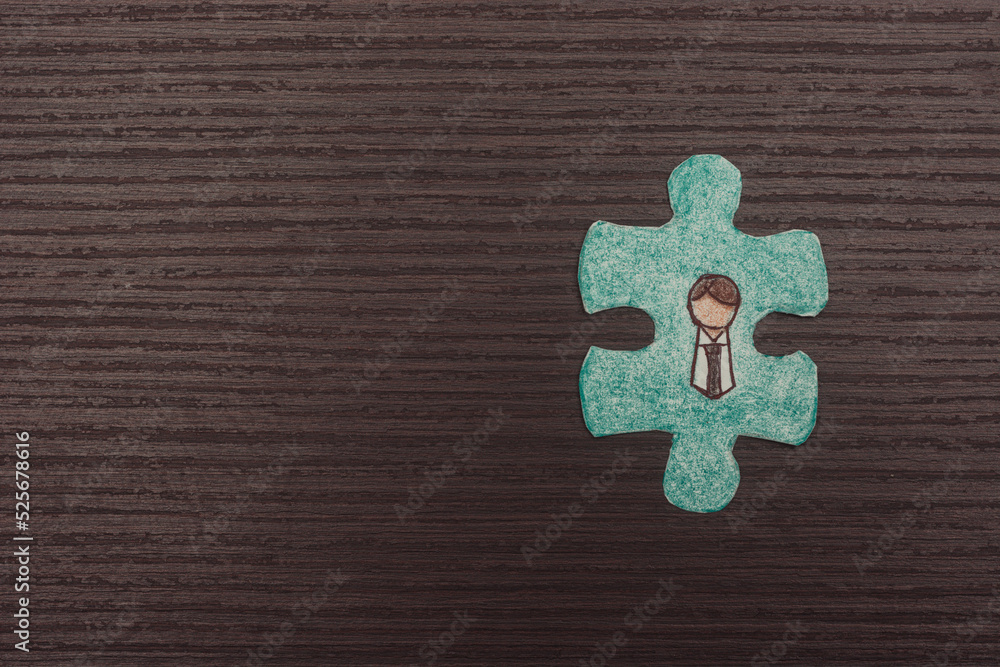 puzzle piece with figure of office worker. Concept of business and hiring of employees in human resources. Isolated wooden background.