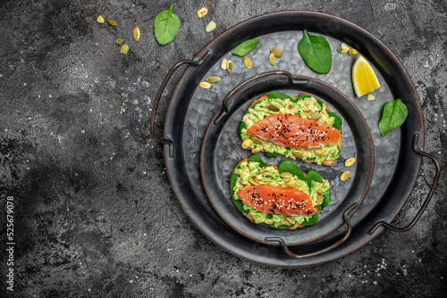 Two toasts whole grain bread with avocado paste and salmon. keto paleo diet. Delicious breakfast or snack. Restaurant menu, dieting, cookbook recipe top view