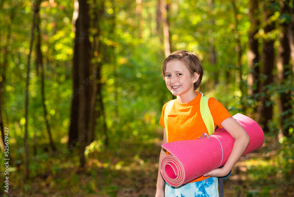 little boy with a backpack and a tourist rug in the forest little boy with a backpack and a tourist rug in the forest