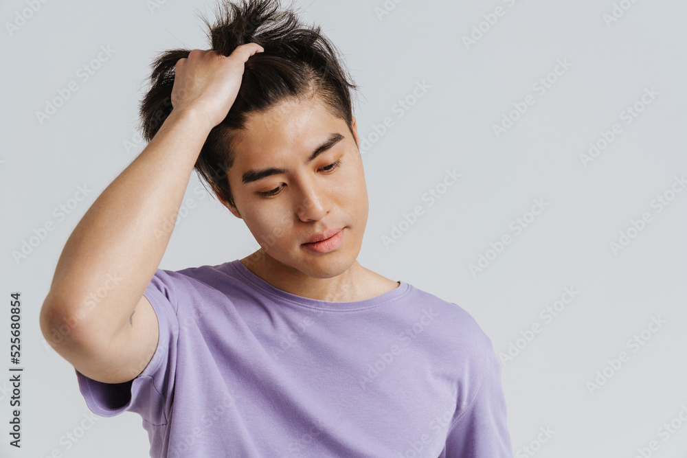 Young handsome asian boy looking downward and touching his hair Young handsome asian boy looking downward and touching his hair