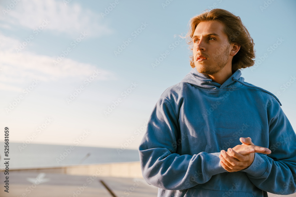 White young man in sportswear standing and looking aside outdoors